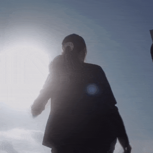 a woman in a black jacket stands in the sunlight