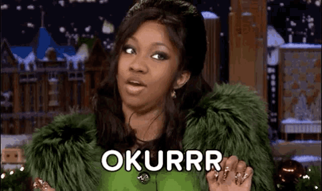 a woman in a green fur coat is making a funny face and saying ok .