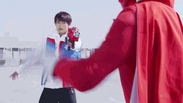 a man in a red cape is holding a gun while another man in a white jacket holds a gun