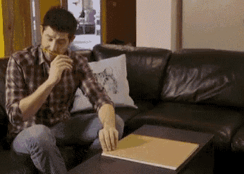 a man is sitting on a couch eating a piece of food