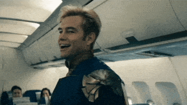 a man in a superhero costume is smiling while sitting on an airplane