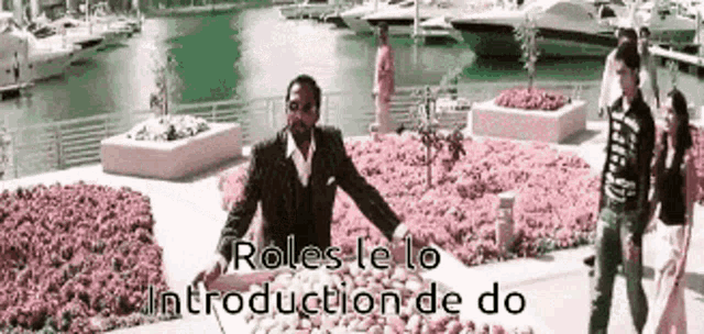 a man standing in front of a bunch of flowers with the words roles le to introduction de do written below him