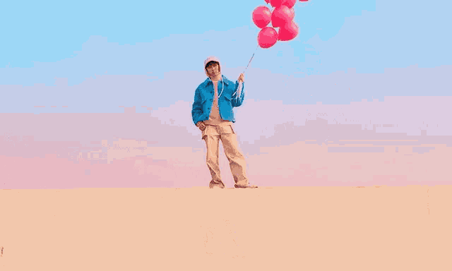 a young man in a blue jacket is holding a bunch of pink balloons .