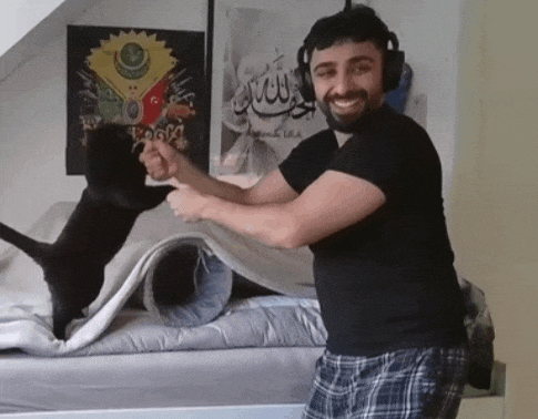 a man wearing headphones is playing with a cat