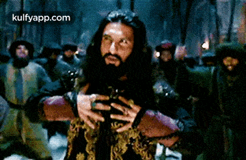 a man with long hair and a beard is standing in front of a group of people .