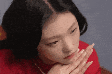 a woman in a red shirt with her hands on her face