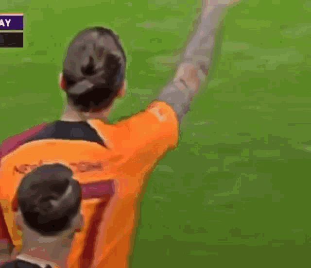 a man in an orange shirt with the number 7 on it stands on a soccer field