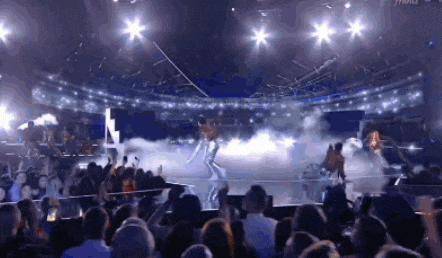 a group of people are dancing on a stage in a stadium .