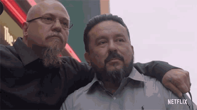 two men standing next to each other with a netflix logo on the bottom right