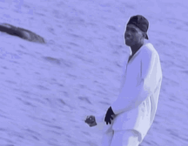 a man in a baseball cap is standing in front of a body of water