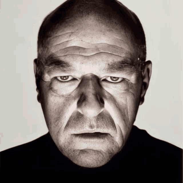 a close up of a man 's face with a black turtleneck on