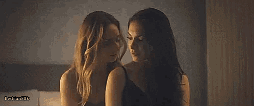 a couple of women are kissing each other in a room .