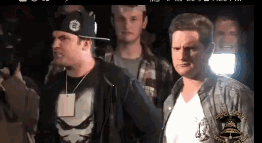 a man in a punisher shirt stands next to another man in a white shirt