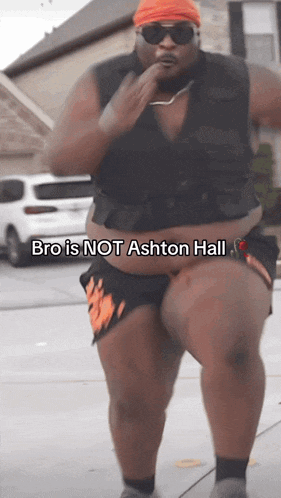 a man with a big belly is walking down the street with the words bro is not ashton hall above him