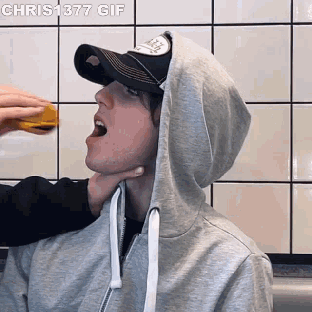 a man wearing a hat and a hoodie is being choked by another man