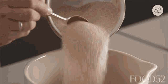 a person is pouring sugar into a bowl with a spoon and the words food52 on the bottom