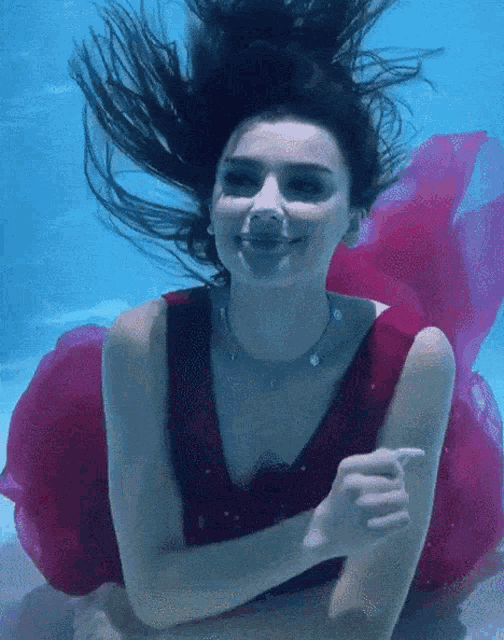 a woman in a red dress is swimming under water