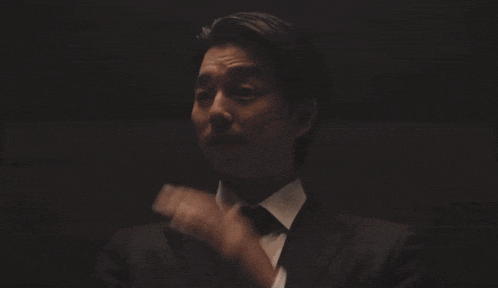 a man in a suit and tie is making a gesture with his hand
