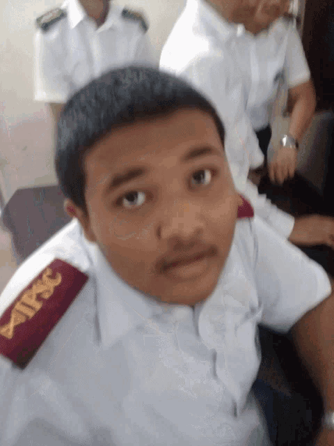 a man wearing a white shirt with a red epaulette that says tpsc