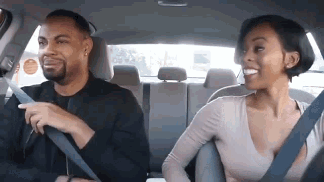 a man and a woman are sitting in a car with seat belts on .