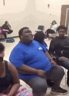 a group of people are sitting in chairs in a room and a man is sitting in the middle of the room .