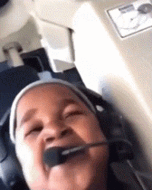 a child wearing headphones and a microphone looks like a pilot