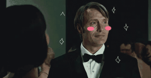 a man in a tuxedo with a bow tie is looking at a woman with diamonds on his face .