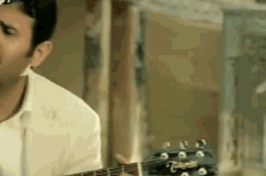 a man is playing a guitar in a room in a blurry photo .