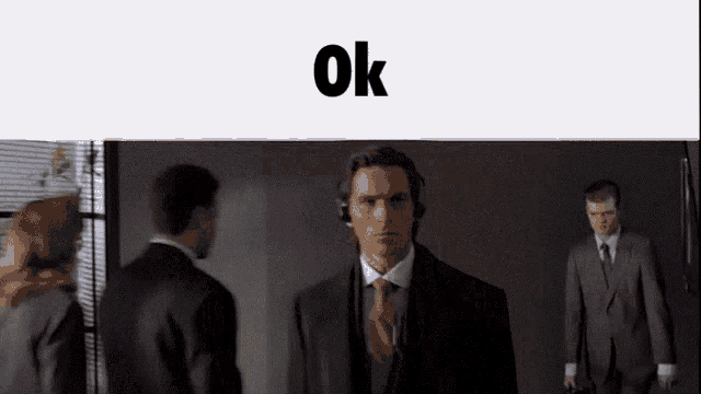 a man in a suit and tie stands in front of a sign that says " ok "