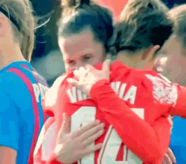 a woman wearing a number 14 jersey is hugging another person