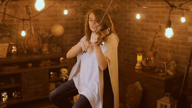 a woman is playing a violin in a room