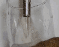 a close up of a faucet pouring water into a glass container .
