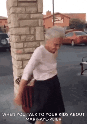 an elderly woman is standing in front of a brick wall and talking to her kids about mark-aye-plier .