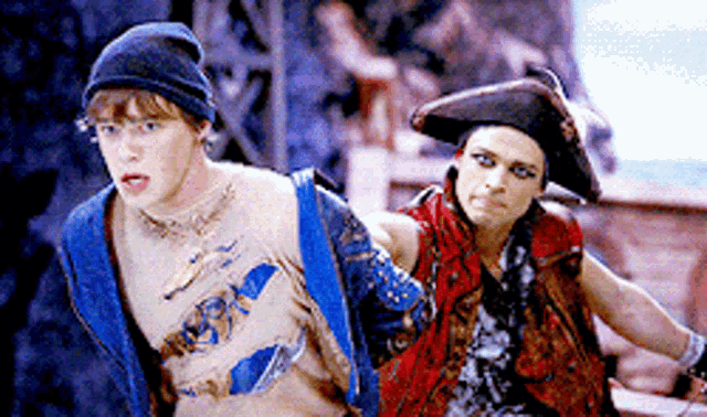 a man in a blue jacket and a man in a red vest are standing next to each other in pirate costumes .