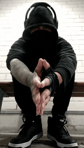 a man wearing headphones and a black hoodie is sitting on a bench