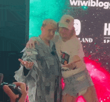 a man and a woman are posing for a picture in front of a sign that says wiwiblog