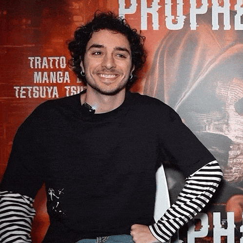 a man smiles in front of a poster that says tratto manga