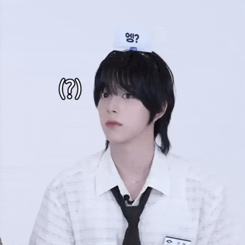 a young man wearing a white shirt and black tie has a card on his head that says ' ? '