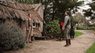 a group of people standing in front of a thatched roof building