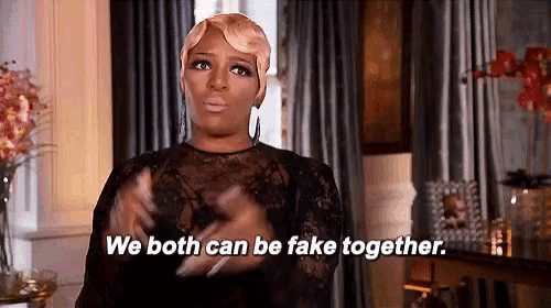 a woman in a black dress is standing in front of a window and saying `` we both can be fake together . ''