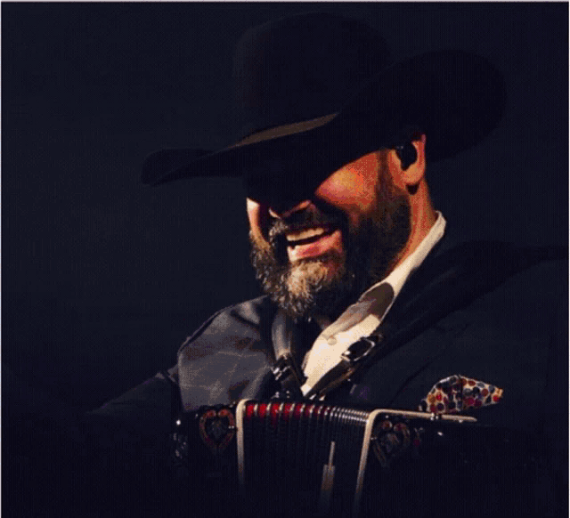 a man in a cowboy hat is singing into a microphone while holding an accordion labeled introable