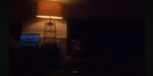 a dark room with a lamp and a laptop on a desk