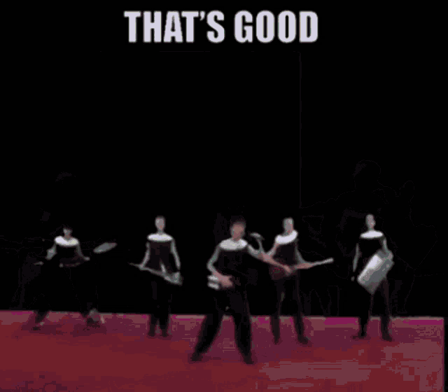a group of people are dancing in front of a wall with the words that 's good on it