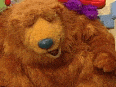 a brown teddy bear with a blue nose is smiling