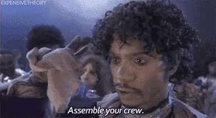 a man with curly hair and a beard is saying `` assemble your crew '' while holding a piece of paper .