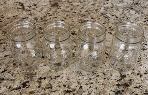 four empty mason jars on a granite counter top