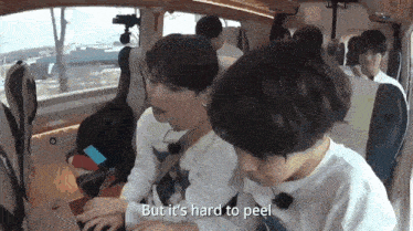 two young boys are sitting in the back seat of a car and one of them is saying but it 's hard to peel