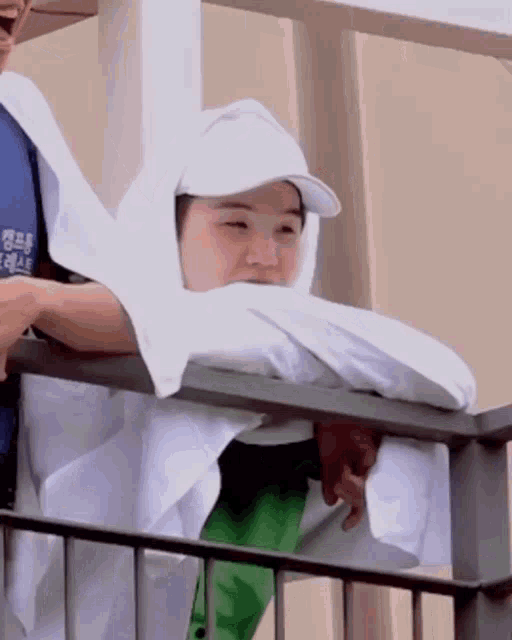 a person with a towel wrapped around their head looks out over a balcony