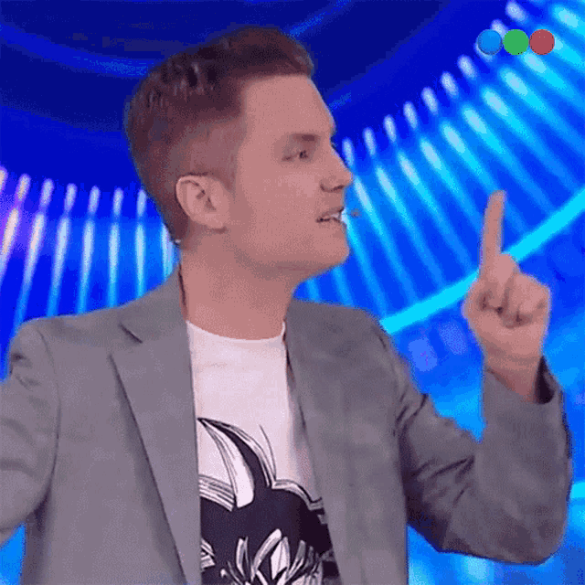 a man in a suit and a white shirt is pointing up with his finger