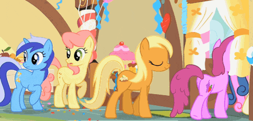 a group of ponies standing next to each other with a cupcake in the background